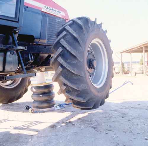 An inflated three bellow, heavy duty Selson Air Jack with a handle, lifting up the front corner and wheel of a tractor.
