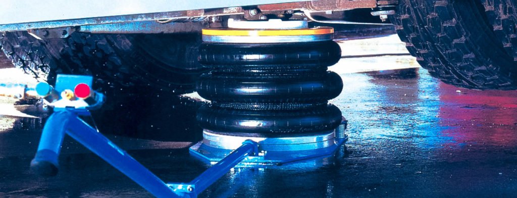A deflated three bellow, heavy duty Selson Air Jack with a handle, placed under a vehicle ready to inflate and lift.