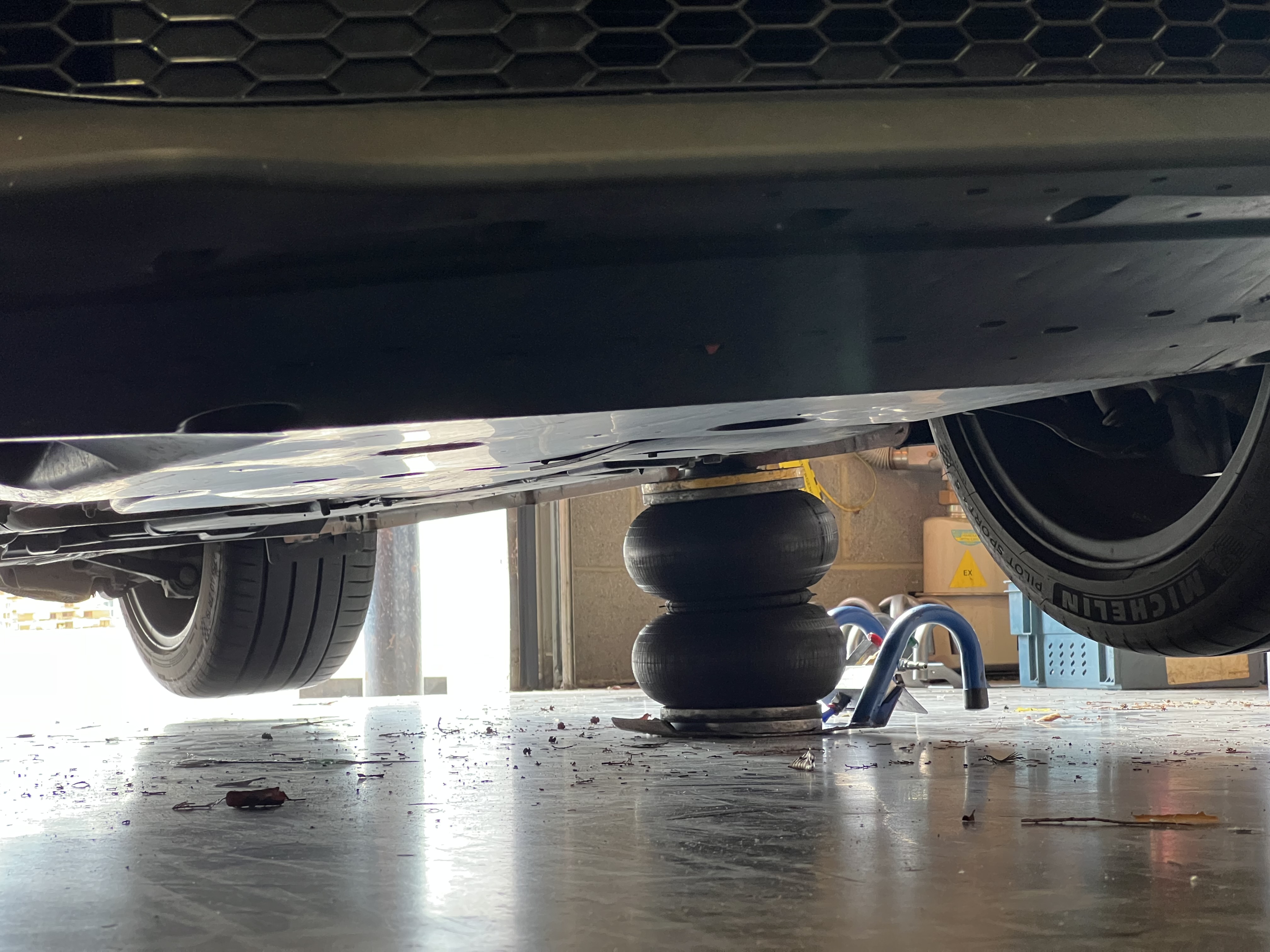 A photo of an inflated two bellow Selson Air jack underneath the body of a vehicle, lifting it up.