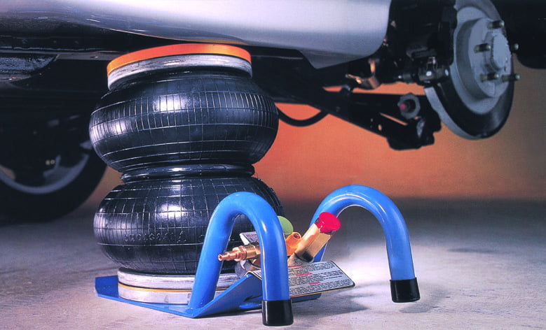 Inflated pneumatic Selson Air Jack lifting a car, with blue handles and control valves visible in the foreground.