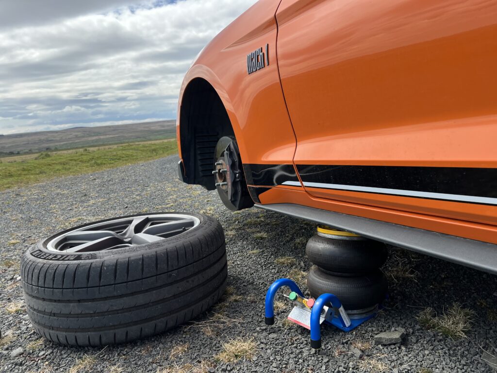 A Selson Air Jack being used to change the tyre on an orange Mustang
