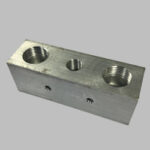 A metal valve manifold with multiple threaded ports for pipe connections